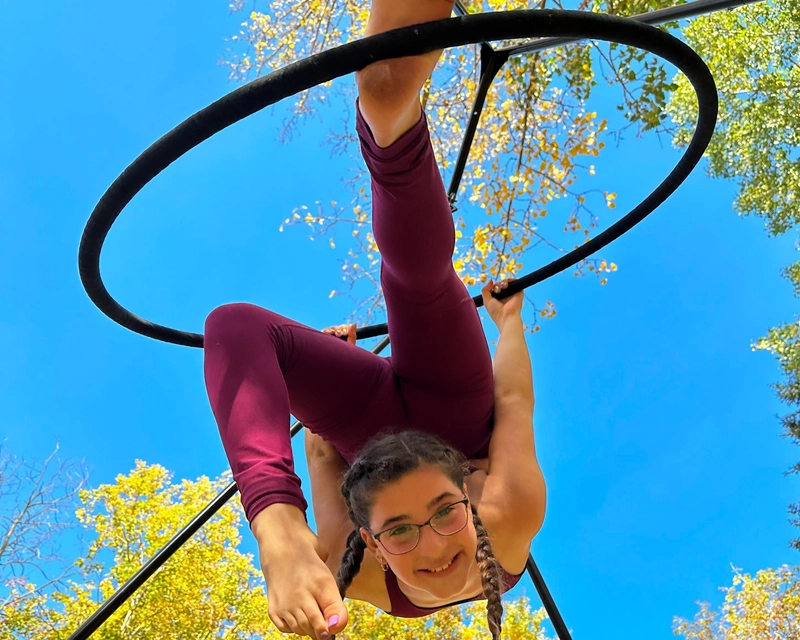 Student swinging from a hoop in an aerial class